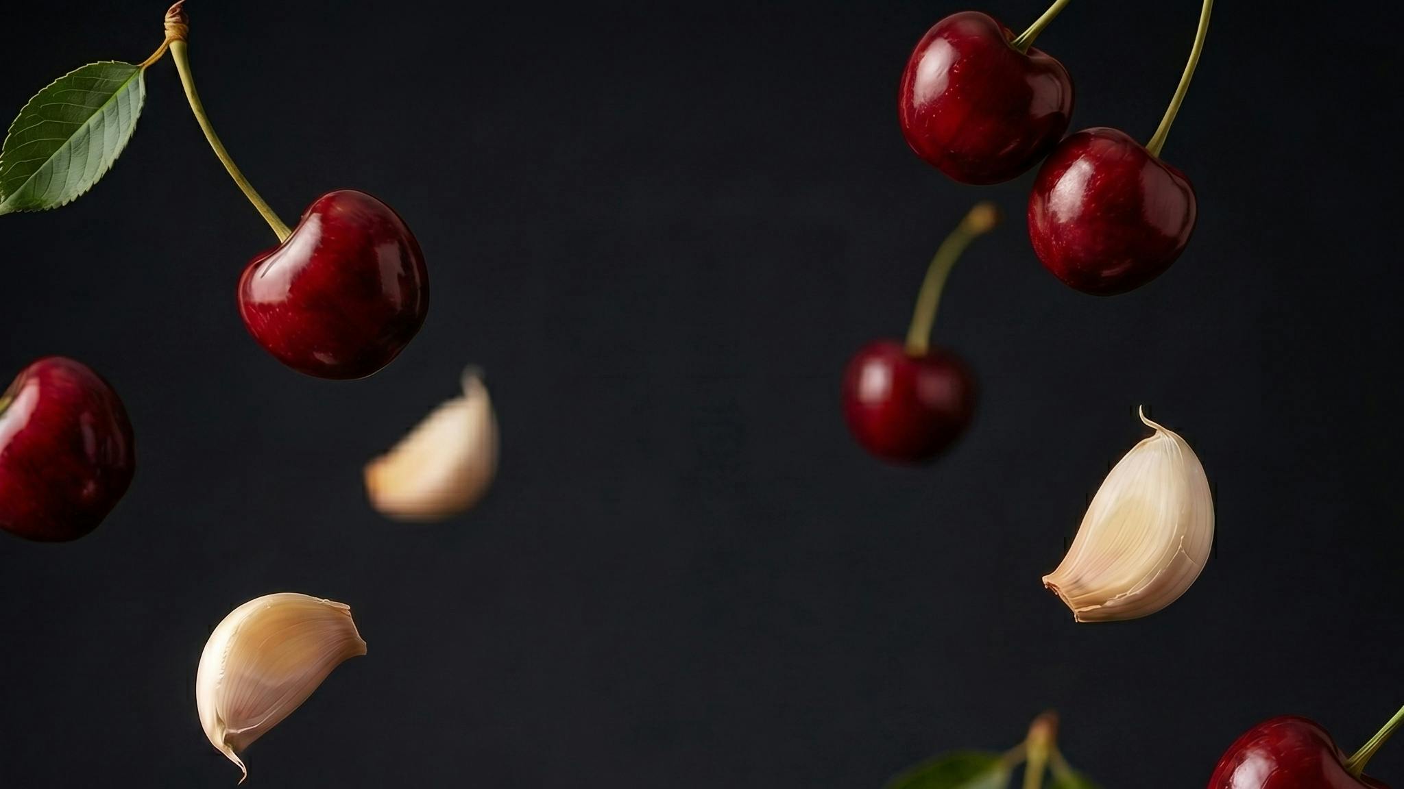 Cherries and garlic floating on a dark background